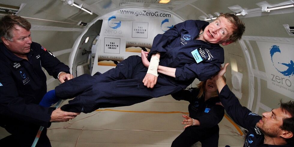 Stephen Hawking sorride mentre tre persone lo fanno girare a mezz'aria durante un volo a gravità zero in un Boeing 727 nel 2007.