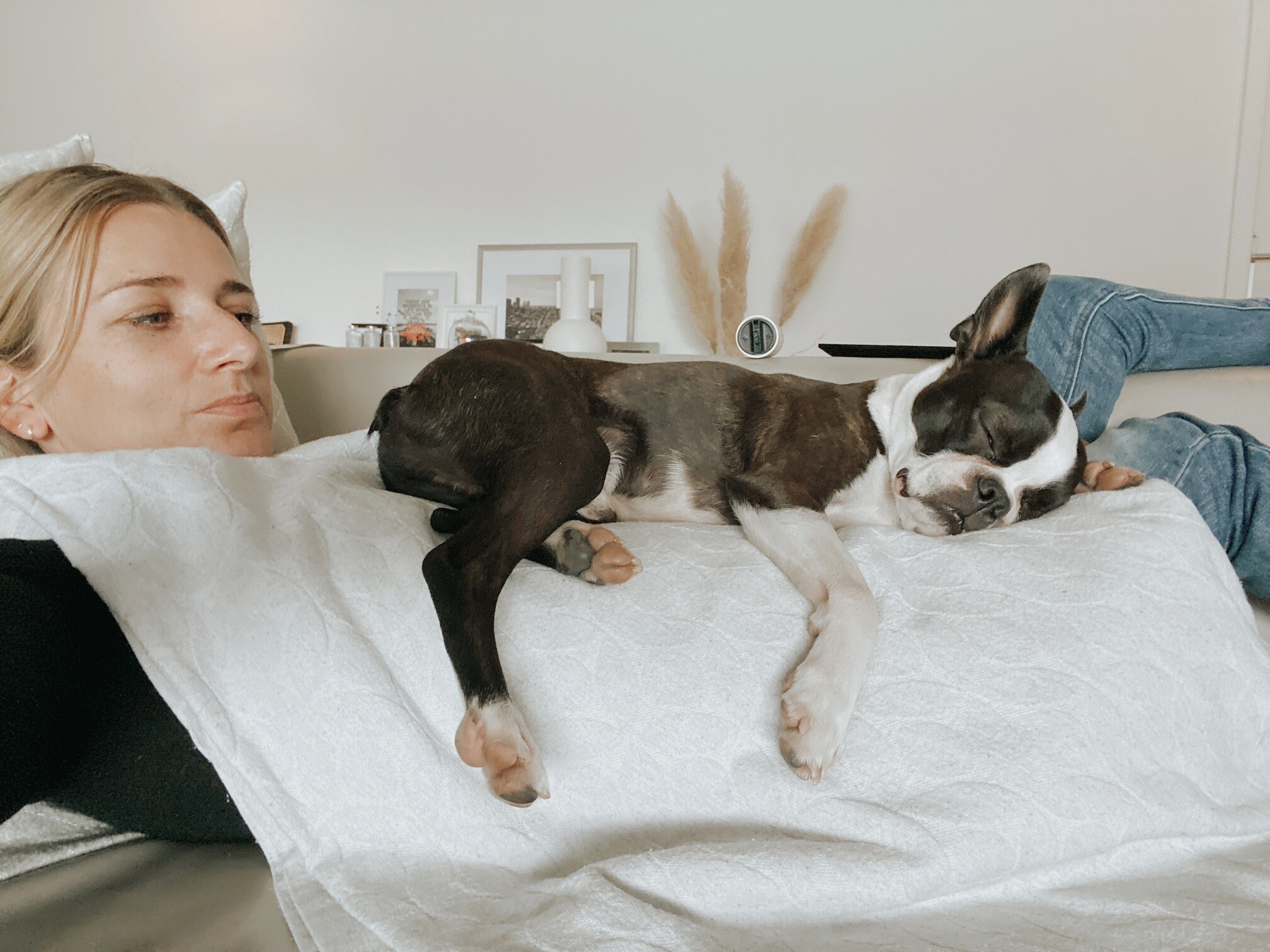 Manuela Schär è sdraiata sul divano, mentre il cane Lui dorme su di lei.