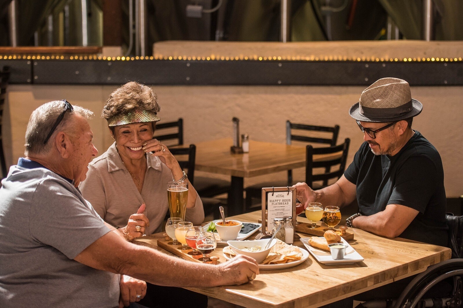 drei fröhliche personen sitzen an einem tisch in einer bar