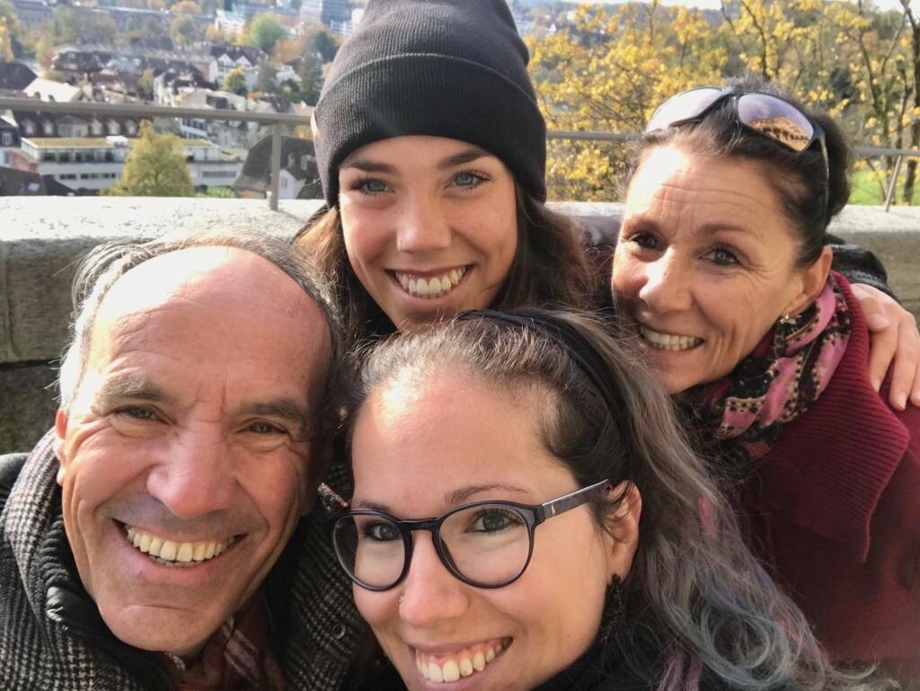 Familie Anesini-Walliser macht ein Selfie und schaut dabei fröhlich in die Kamera.