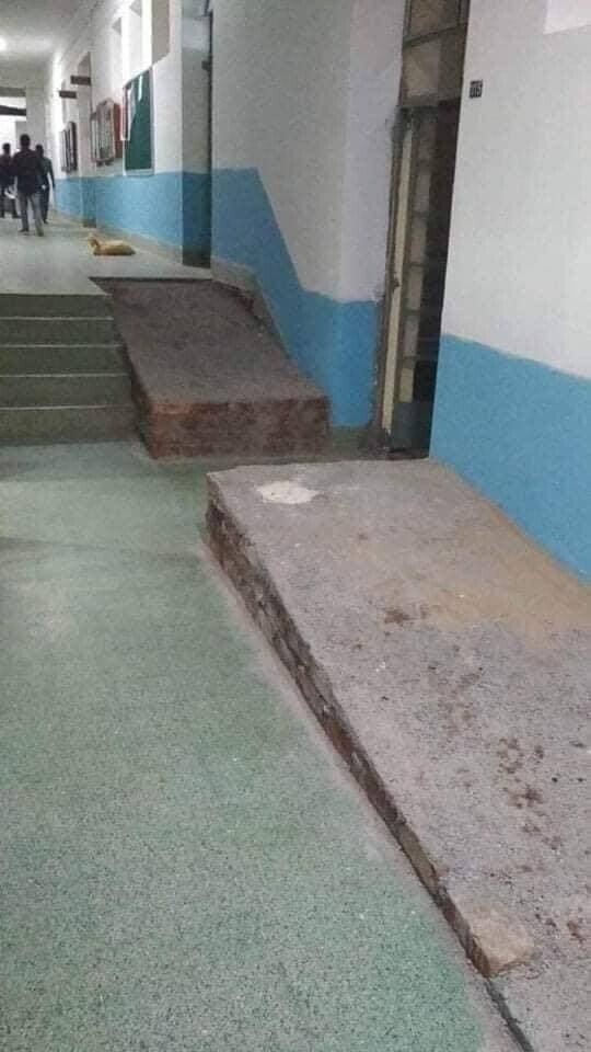 Une rampe à la pente douce dans un bâtiment est coupée en deux pour dégager l’accès à une porte.