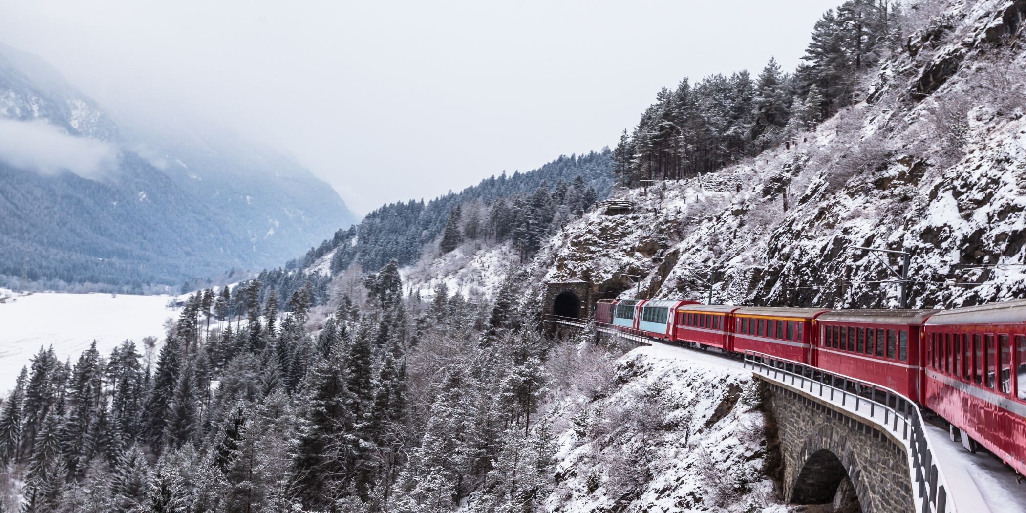 Glacier Express entering a tunnel in a stunning winter landscape.