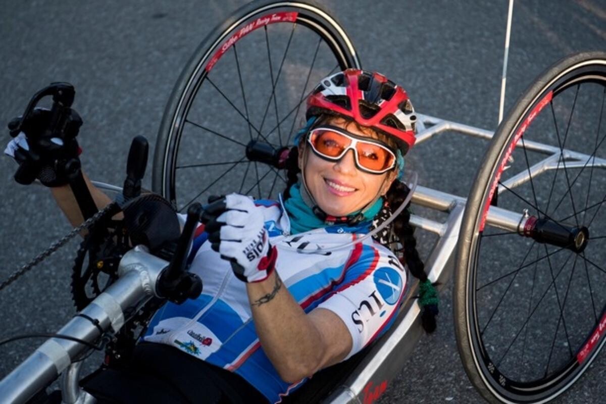 Silke Pan poses with her hand bike, helmet and glasses.